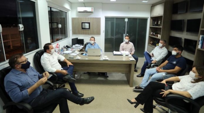 prefeitos e secretários de saúde em reunião em sala; todos sentados em poltronas, usando mácaras