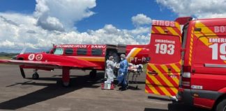 Carro vermelho do samu e aeronave vermelha paradas enquanto profissionais com EPIs transferem paciente de Covid-19 de Chapecó para Itajaí