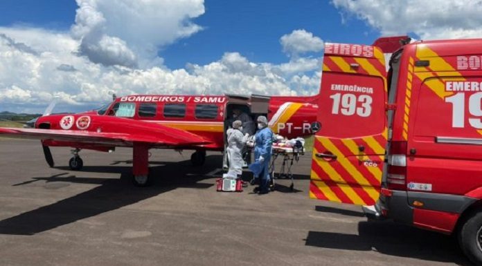 Carro vermelho do samu e aeronave vermelha paradas enquanto profissionais com EPIs transferem paciente de Covid-19 de Chapecó para Itajaí