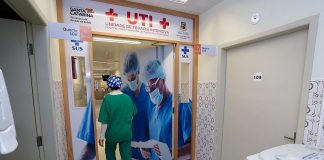 profissional de saúde com trajes entra em porta da ala de uti do hospital de nova trento