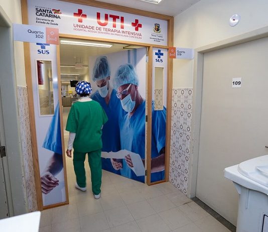 Governo anuncia decreto de emergência estadual no atendimento de saúde profissional de saúde com trajes entra em porta da ala de uti do hospital de nova trento