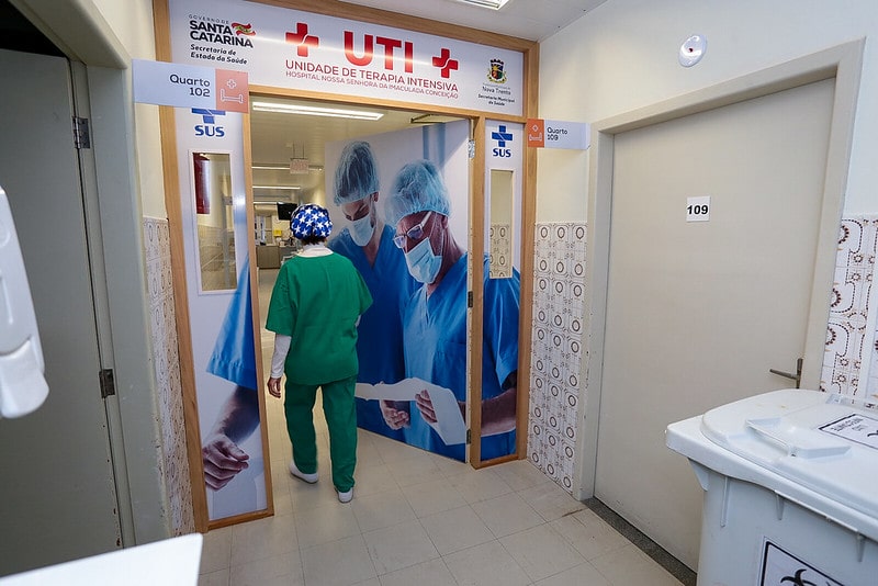 profissional de saúde com trajes entra em porta da ala de uti do hospital de nova trento