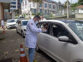 profissional de saúde ao lado de carro em fila de drive no dia em que são josé vacinou 25% dos idosos com mais de 85 anos