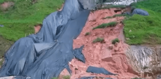 acúmulo de chuva fez com que novos deslizmaentos ocorressem na via expressa - imagem mostra barranco desmoronado com parte de lona, parte de terra, e parte de grama