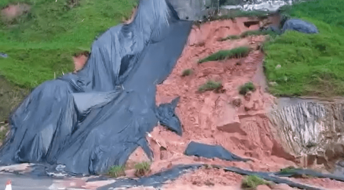 acúmulo de chuva fez com que novos deslizmaentos ocorressem na via expressa - imagem mostra barranco desmoronado com parte de lona, parte de terra, e parte de grama