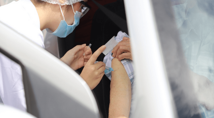 Vacinação na Grande Florianópolis contra a Covid-19: profissional da saúde vacinando idoso dentro do carro