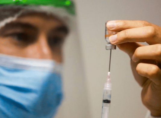 Santa Catarina tem 323 mil doses aplicadas contra Covid-19: Profissional da saúde, equipado com EPI, colocando a vacina na seringa