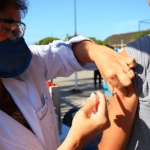 Vacinação contra Covid-19 em idosos de 76 e 77 anos: Profissional da saúde aplicando a dose em idoso