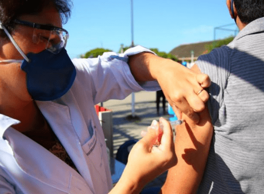 Vacinação contra Covid-19 em idosos de 76 e 77 anos: Profissional da saúde aplicando a dose em idoso