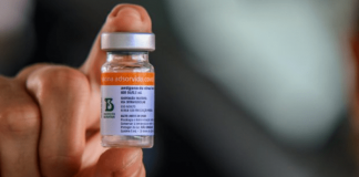 Falso anúncio: close em uma mão segurando dose da vacina contra Covid-19