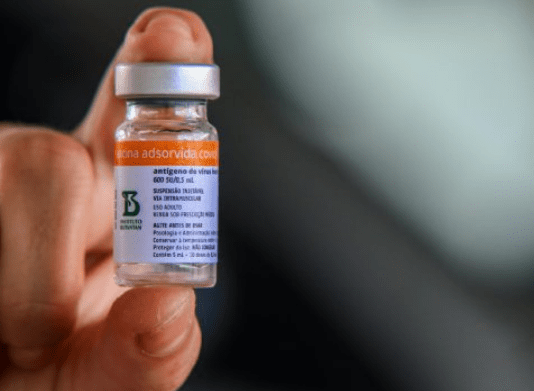 Falso anúncio: close em uma mão segurando dose da vacina contra Covid-19