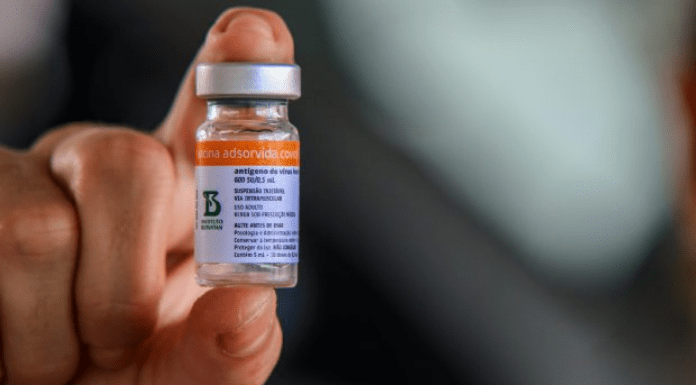 Falso anúncio: close em uma mão segurando dose da vacina contra Covid-19