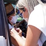 profissional de saúde aplica vacina no braço de idoso dentro de carro - Vacinação contra Covid em idosos a partir de 78 anos tem início em Palhoça