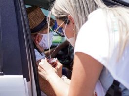 profissional de saúde aplica vacina no braço de idoso dentro de carro - Vacinação contra Covid em idosos a partir de 78 anos tem início em Palhoça