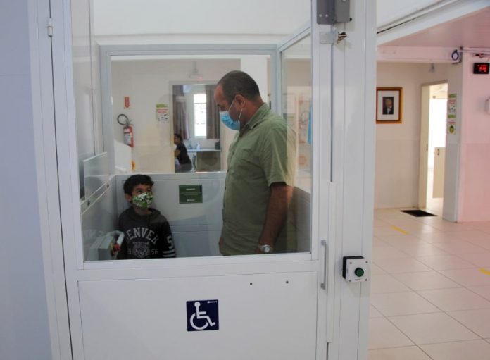 homem e garoto dentro de elevador com acessibilidade para cadeirantes em escola