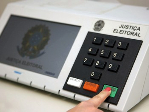 mão feminina pressiona botão verde da urna eletrônica - candidatura fictícia pode resultar em cassações em são josé