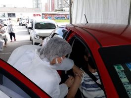mulher se inclina para vacinar idoso dentro de carro - continua a vacinação contra covid em são josé