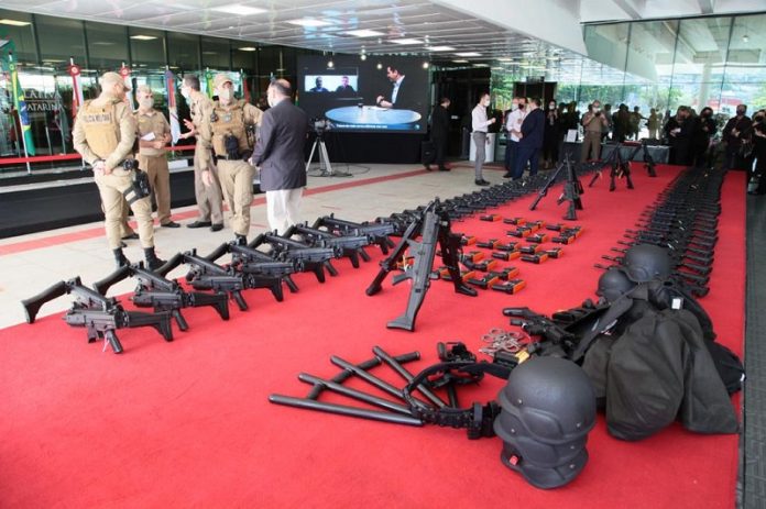 No tapete vermelho da Alesc os armamaentos estão distribuídos lado a lado. Ao fundo da foto pessoas reunidas e mais a frente um grupo de policiais militares fardados. A Polícia Militar de SC recebeu hoje viaturas e equipamentos em ato simbólico na assembleia.