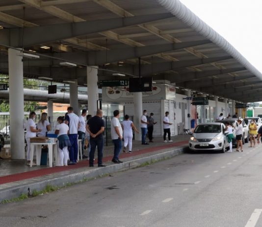 estação palhoça, onde é feita a vacinação por drive-thru; profissionais de saúde na plataforma; fila de carros; policial na pista