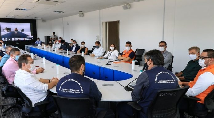 prefeitos reunidos em grande mesa em formato de "U" na instalação do Centro Integrado de Ações Contra a Covid; todos de máscara