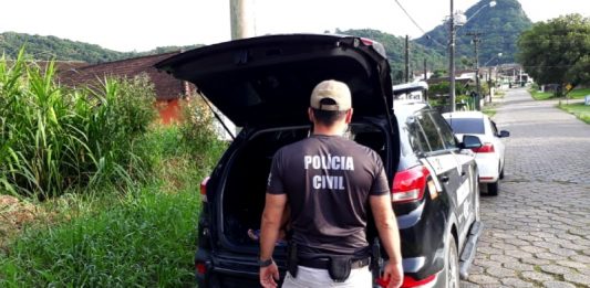 policial civil atrás de uma caminhonete da pc com porta-malas aberto estacionada em rua de paralelepípedo na deflagração da operação rescaldo