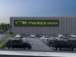 Projeto da arena de esportes de areia que será sediada em Biguaçu. Com um estacionamento e alguns carros, ao fundo se vê a arena identificada com letras verdes "maniacs arenas"
