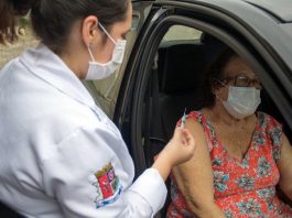São José conclui vacinação da primeira dose em idosos acima de 80 anos profissional de saúde com agulha na mão ao lado de senhora sentada em carro com a porta aberta