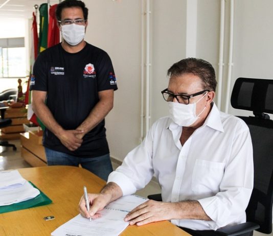 São José destina R$ 1,3 milhão para a área do esporte de rendimento Sentado em uma cadeira preta, o prefeito Orvino usa camisa branca de manga comprida, além de óculos de armação preta e máscara branca. Ele assina um convênio que destina mais de R$ 1 milhão para a área do esporte em São José. Próximo a ele, em pé, um dos representante da área acompanha a assinatura, ele usa óculos de grau, máscara branca e camiseta preta.