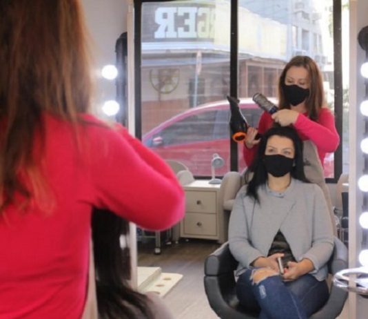 Falta amparo para pequenos negócios enfrentarem restrições em SC Foto de um espelho, em que aparece uma mulher com secador mexendo no cabelo de uma moça que está sentada, ambas usam máscara. Os empreendedores de SC precisam lidar com o avanço da pandemia em meio a medidas restritivas e falta de amparo do governo.