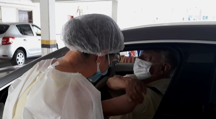 profissional de saúde aplica dose em braço de homem dentro de carro - São José inicia vacinação de idosos de 76 e 77 anos