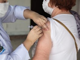 profissional de saúde aplica injeção no braço de senhora - vacinação de idosos em são josé