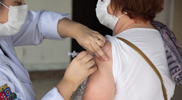 profissional de saúde aplica injeção no braço de senhora - vacinação de idosos em são josé