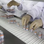 linha de produção de doses de vacinas, com pessoas usando luvas mexendo nas ampolas - consório de prefeituras solicita compra da sinovac