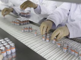 Consórcio de prefeituras faz pedido de compra de 15 milhões de doses de vacinas linha de produção de doses de vacinas, com pessoas usando luvas mexendo nas ampolas - consório de prefeituras solicita compra da sinovac