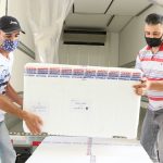 dois homens usando máscara carregam caixa de isopor - Florianópolis e São José receberão 17 mil doses da vacina Pfizer na próxima semana