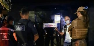 agentes de segurança em frente a um dos bares de florianópolis fiscailizados; porta de vidro fechada com placa "interditado"