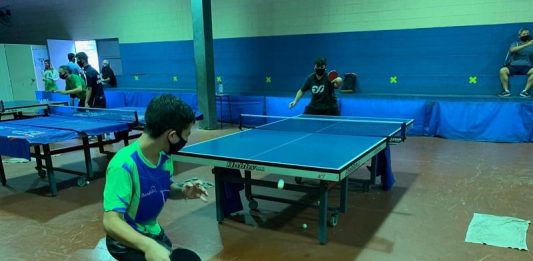 dois jovens de máscara jovando tênis de mesa, um dos projetos comunitários na capital