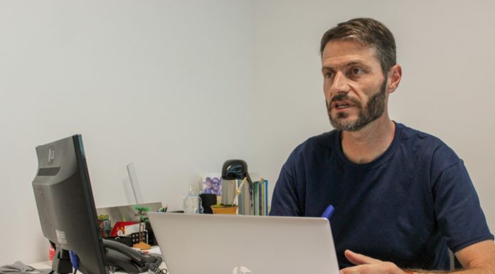 Câmara de São José aprova maior transparência em gastos de publicidade vereador andré guesser falando sentado em mesa com computador e notebook