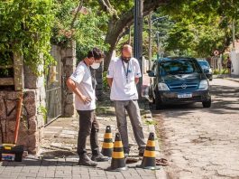 dois fiscais usando máscaras olham para buraco no chão em calçada com cones em volta - fiscalização de ligações de esgoto na lagoa da conceição