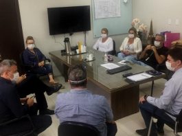 Entidades vão destinar recursos para obras no Hospital Regional de São José Em uma sala com uma mesa retangular ao centro, oito pessoas sentadas de forma circular conversam enquanto usam máscaras. Nessa reunião, entidades empresariais informaram a doação de recursos para obras do hospital regional de são josé.