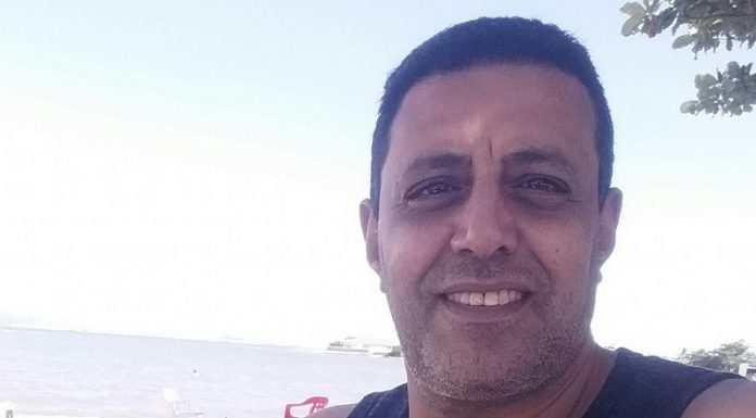 O motorista de aplicativo Amr Mostafa posa sorridente com uma regata preta, ele tem cabelos escuros e pele clara, Amr foi baleado em São José em uma corrida com três passageiros