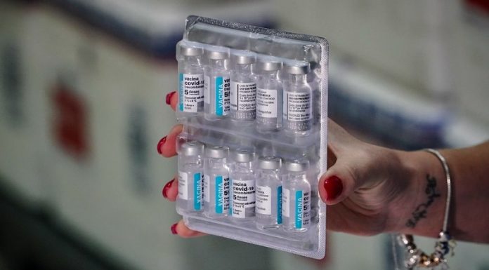 mulher segura doses de vacinas presas em tablete de transporte - novo lote de vacinas chega em sc com 229 mil doses