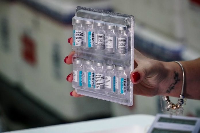 mulher segura doses de vacinas presas em tablete de transporte - novo lote de vacinas chega em sc com 229 mil doses