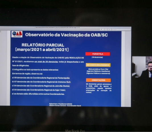 Tela do computador mostra uma apresentação em tela azul sobre os números do observatório da vacinação em SC, da OAB/SC, mostrando os números de denúncias do primeiro mês
