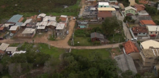Vista aérea mostra área verde com ruas de terra e uma aparentemente asfaltada. Há diversas casas nessas ruas, representando as ocupações irregulares em Florianópolis, que descumpriu acordos em relação ao problema.