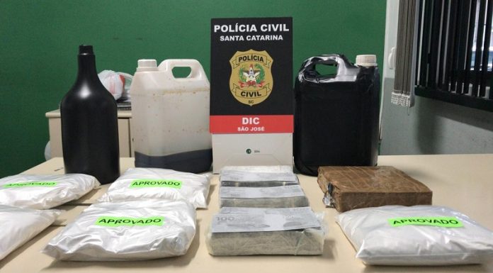 uma mesa com uma garrafa e galões, além de pacotes com substâncias químicas que seriam usadas para aplicar o golpe do dinheiro preto, aplicado por um estelionatário presa nesta semana