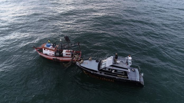 Visão aérea mostra duas embarcações no mar, uma de fiscalização e outra que realizava pesca ilegal. O pescador foi preso durante a ação de fiscalização da PF e Ibama.