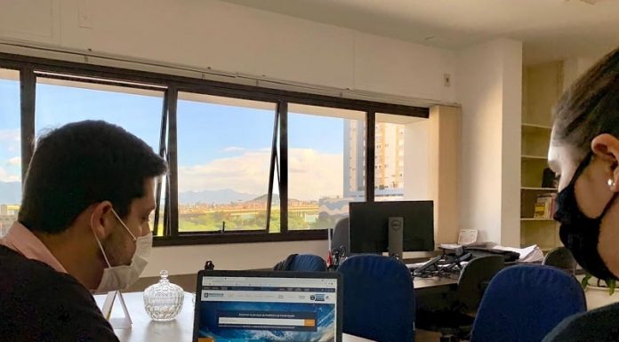 homem e mulher usando máscaras sentados em frente a notebook - programa de ensino prático do serviço público em florianópolis