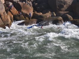 Seis pessoas são resgatadas em Florianópolis após embarcação colidir em costão Na foto se vê o mar e ao fundo as pedras do costão com algumas pessoas nelas. Ontem, os bombeiros fizeram o resgate de seis pessoas que estavam no mar após a embarcação em que estavam colidir com o costão.