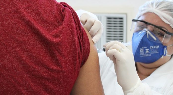 profissional de saúde usando máscara e óculos de proteção faz aplicação de vacina no braço de homem - são josé vacina contra influenza
